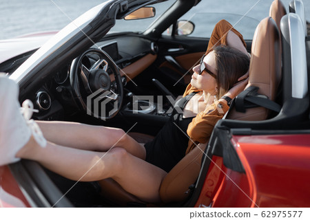Woman enjoying summer vacation while traveling by car Woman enjoying summer vacation while traveling by car 62975577