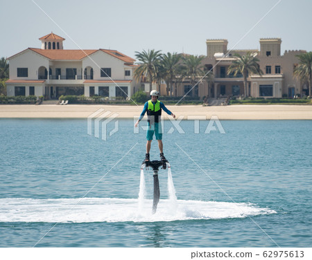 Water extreme sport. The guy is flying at the aquatic flyboard. Extreme rest on the sea 62975613
