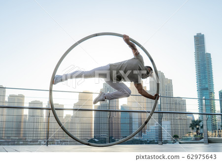 Cyr Wheel artist with cityscape background of Dubai during sunset Cyr Wheel artist with cityscape background of Dubai during sunset 62975643
