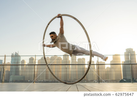 Cyr Wheel artist with cityscape background of Dubai during sunset Cyr Wheel artist with cityscape background of Dubai during sunset 62975647