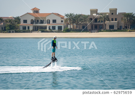 Water extreme sport. The guy is flying at the aquatic flyboard. Extreme rest on the sea 62975659