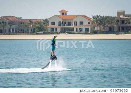 Water extreme sport. The guy is flying at the aquatic flyboard. Extreme rest on the sea 62975662