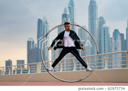 Cyr Wheel artist wearing black and white smart clothes with cityscape background of Dubai during Cyr Wheel artist wearing black and white smart clothes with cityscape background of Dubai during 62975734