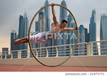 Cyr Wheel artist with cityscape background of Dubai during sunset Cyr Wheel artist with cityscape background of Dubai during sunset 62975751