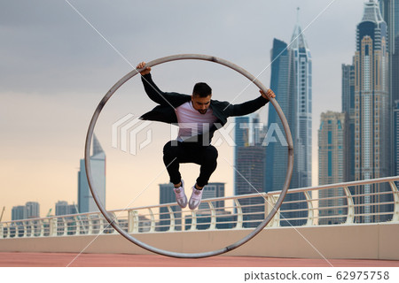 Cyr Wheel artist wearing black and white smart clothes with cityscape background of Dubai during 62975758