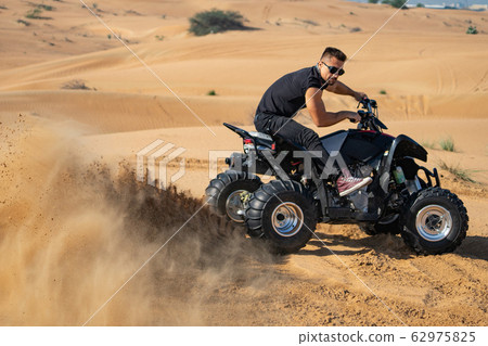 Muscular Man Riding Atv In the Desert Muscular Man Riding Atv In the Desert 62975825