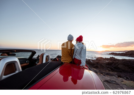 Lovely couple on the beach near the car on a sunset Lovely couple on the beach near the car on a sunset 62976867
