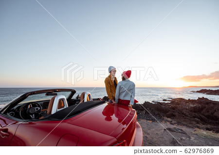 Lovely couple on the beach near the car on a sunset Lovely couple on the beach near the car on a sunset 62976869