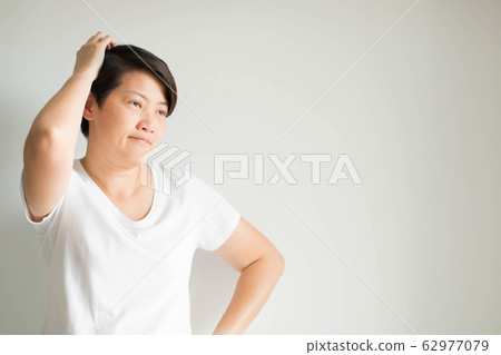 Asian woman sighing and scratching head, thinking what to do with a problem on white background. Asian woman sighing and scratching head, thinking what to do with a problem on white background. 62977079