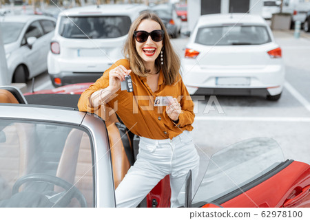 Happy woman with keys near the car at the parking 62978100