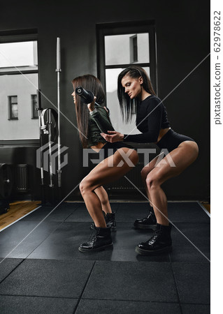 Full length shot of two young women in sportswear standing together in the gym. Sister in a health club looking at camera. Full length shot of two young women in sportswear standing together in the gym. Sister in a health club looking at camera. 62978622
