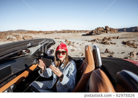 Woman traveling by cabriolet car on the desert road 62978826