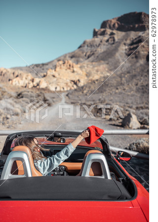 Woman traveling by cabriolet car on the desert road 62978973