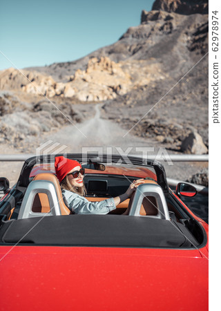 Woman traveling by cabriolet car on the desert road 62978974