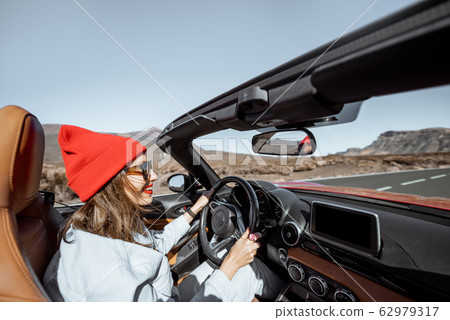 Woman traveling by cabriolet car on the desert road 62979317