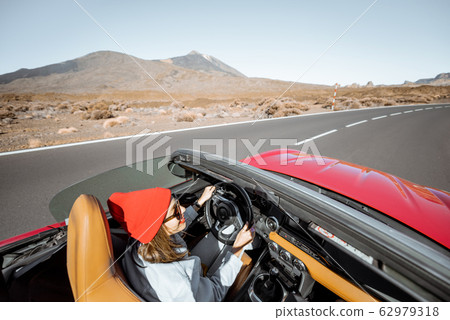 Woman traveling by cabriolet car on the desert road 62979318