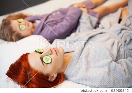 Mother and daughter are doing spa treatments at home in bed Mother and daughter are doing spa treatments at home in bed 62980845