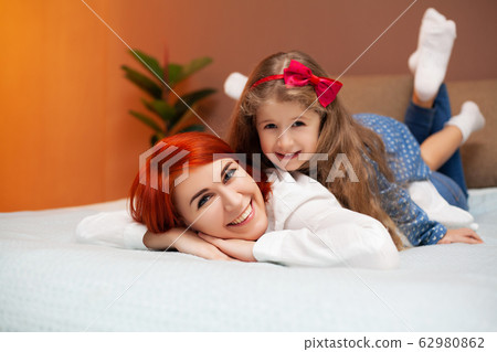 Mom and daughter resting in bed at home Mom and daughter resting in bed at home 62980862