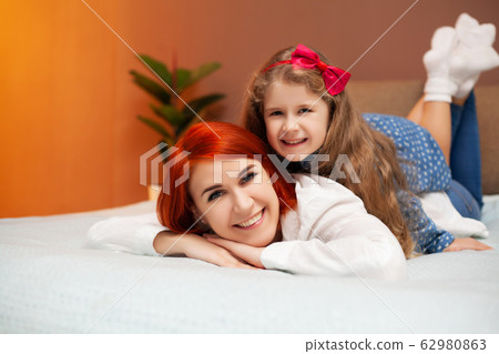 Mom and daughter resting in bed at home Mom and daughter resting in bed at home 62980863