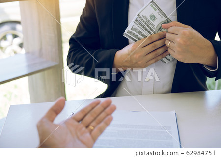 Businessman putting stack of money bills in his 62984751