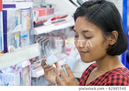 A young woman chooses cosmetics at a store. Asian 62985548