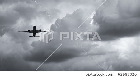 Airplane flying on dark sky and white clouds. 62989020