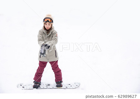 A woman snowboarding 62989627