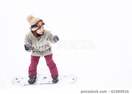 A woman snowboarding 62989916