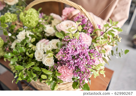 Floral shop concept . Florist woman creates flower arrangement in a wicker basket. Beautiful bouquet of mixed flowers. Handsome fresh bunch. Flowers delivery. Floral shop concept . Florist woman creates flower arrangement in a wicker basket. Beautiful bouquet of mixed flowers. Handsome fresh bunch. Flowers delivery. 62990267