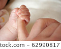 Photo material: baby's hand holding a finger 62990817