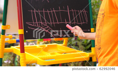 A boy in the open air draws with chalk on the Board A boy in the open air draws with chalk on the Board 62992046