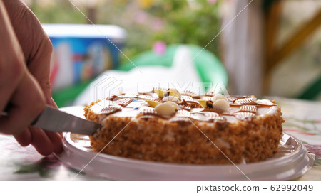 Male hand cutting birthday cake with knife. Birthday party dessert Male hand cutting birthday cake with knife. Birthday party dessert 62992049