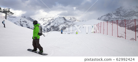 Snowy ski slope with snowboarders and skiers in Snowy ski slope with snowboarders and skiers in 62992424