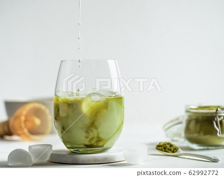 Iced Matcha Latte Tea with pouring milk drops 62992772
