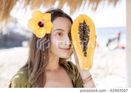 Summer girl with papaya fruit at the beach resort Summer girl with papaya fruit at the beach resort 62993087