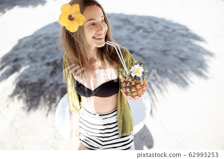 Woman with exotic cocktail at the beach resort 62993253