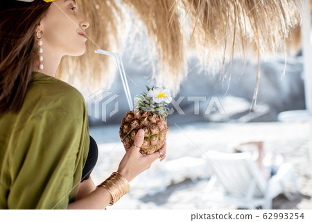 Woman with exotic cocktail at the beach resort 62993254