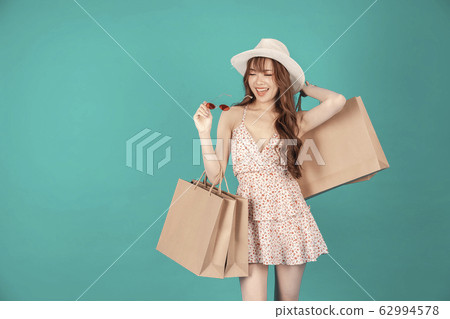 Asian girl carrying shopping bags with summer dress and enjoys shopping. Asian girl carrying shopping bags with summer dress and enjoys shopping. 62994578
