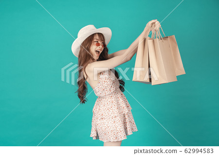 Asian girl carrying shopping bags with summer dress and enjoys shopping. Asian girl carrying shopping bags with summer dress and enjoys shopping. 62994583