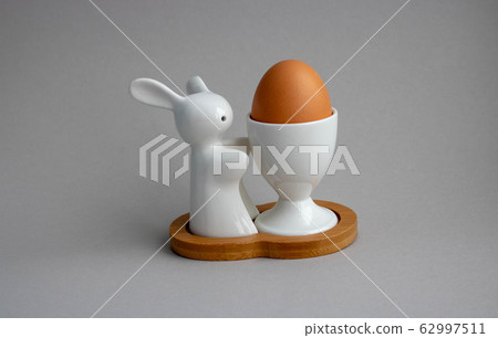 Easter bunny rabbit with brown egg on gray background. Easter holiday concept 62997511