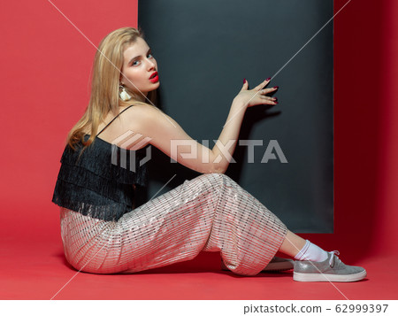 Sitting woman in studio with red background with Sitting woman in studio with red background with 62999397