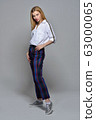 Beautiful blonde woman in white shirt and checked trousers 63000065