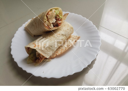 Chicken burrito warp serve on white plate against Chicken burrito warp serve on white plate against 63002770