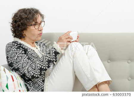 mature woman on the sofa with a phone mature woman on the sofa with a phone 63003370
