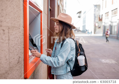 Woman using ATM on the street 63003718