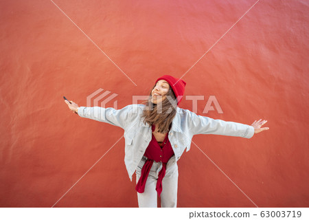 Happy woman on the red background outdoors 63003719