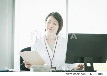 White coat woman desk work White coat woman desk work 63004089