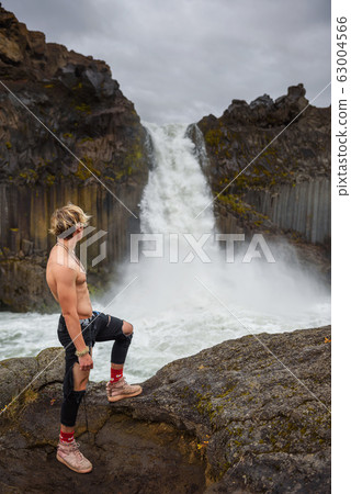 Shirtless and muscular boy looks at the Aldeyjarfoss waterfall in Iceland 63004566