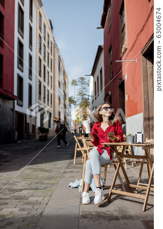Woman with phone and coffee on the cafe terrace outdoors 63004674