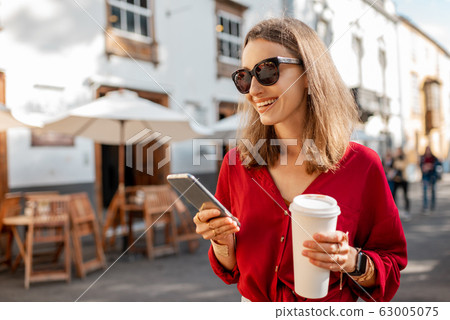Woman with coffee and phone in the old city 63005075